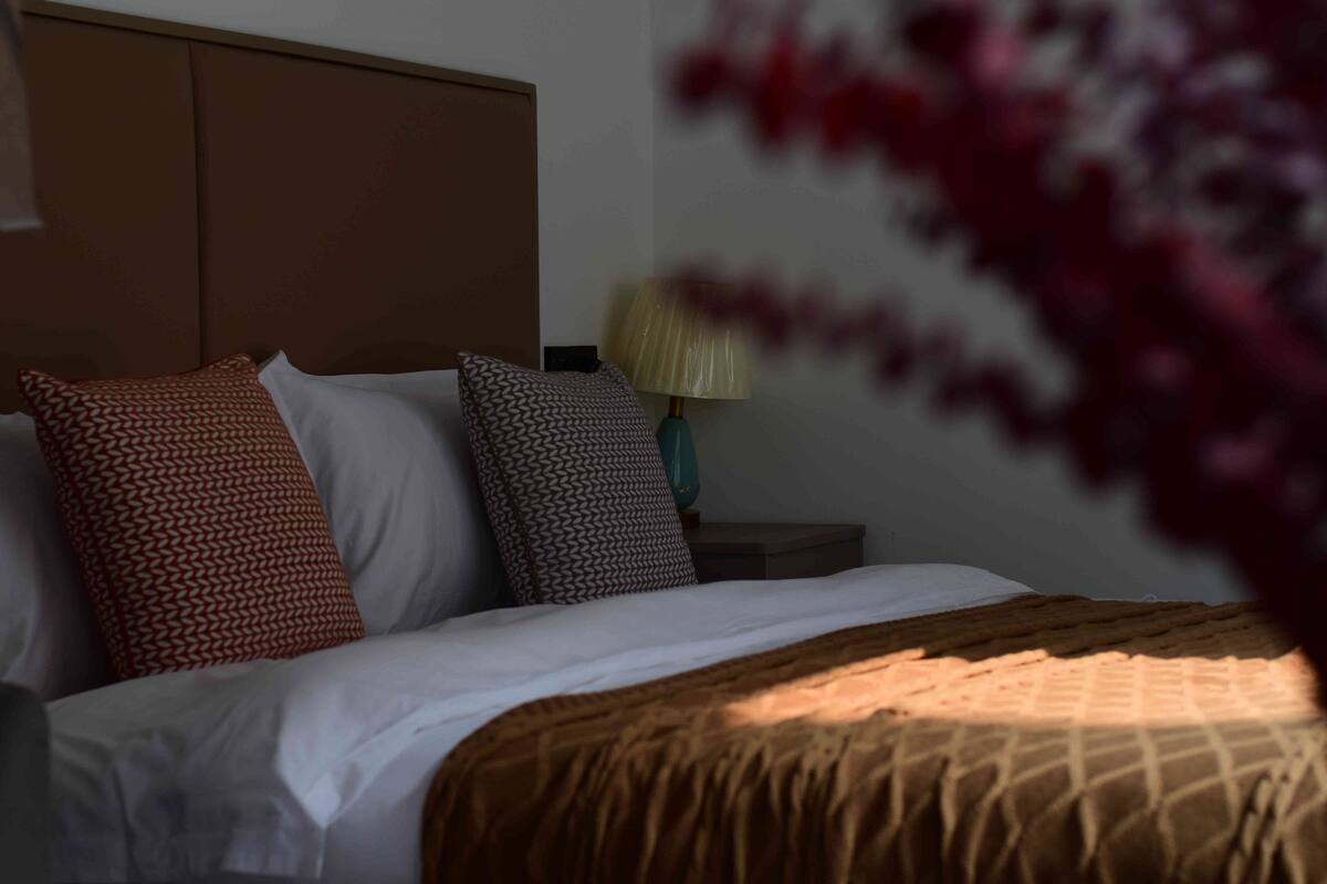 A bed with patterned pillows, a bedside lamp, and a wooden headboard.
