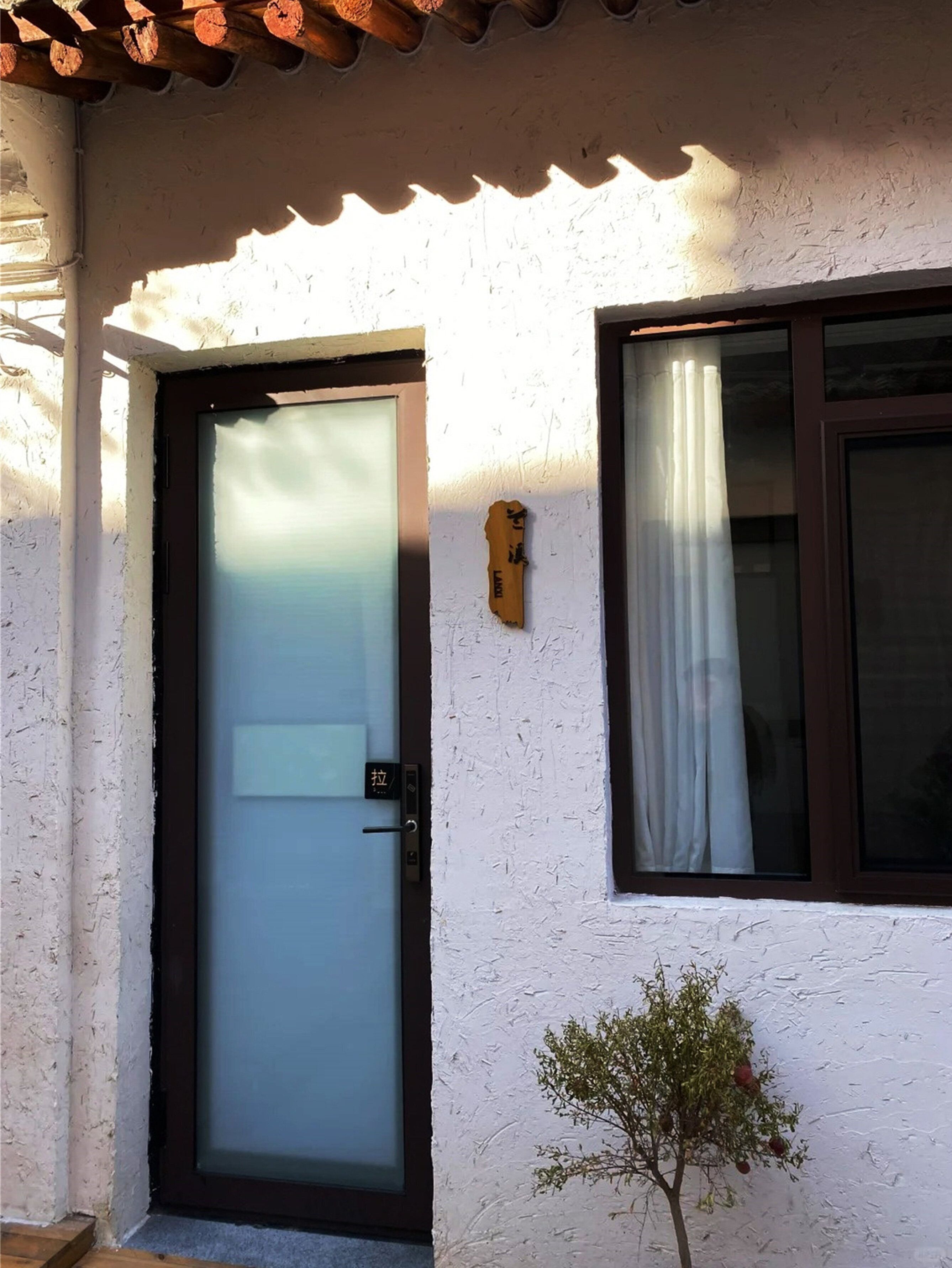 A building with a frosted glass door, a small window with a curtain, and a textured wall.