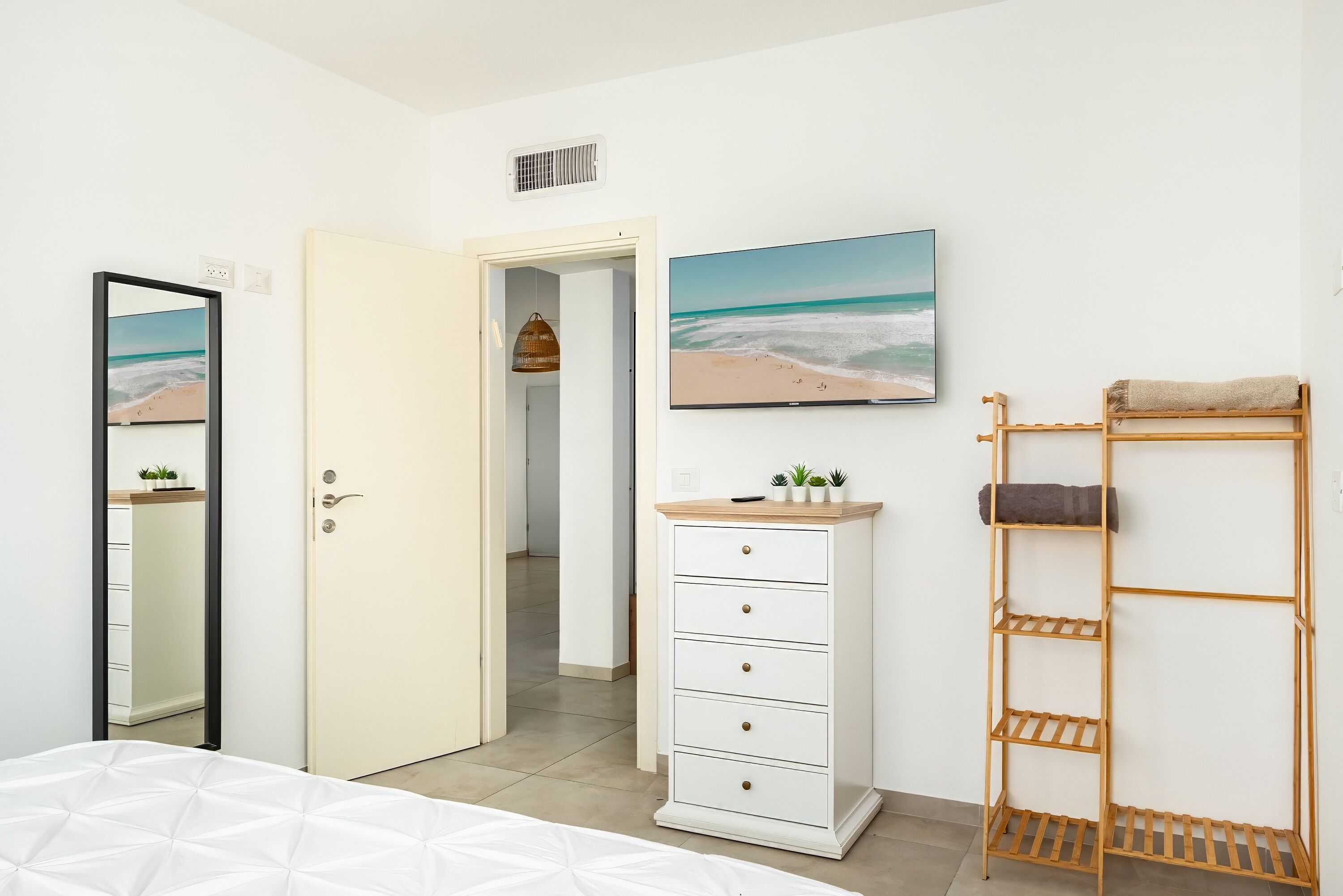 A bedroom with a bed, a dresser, a TV, and a shelf.