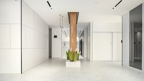 A modern, spacious hallway with a central wooden column, white walls, and a marble floor. - MAMAD - Sea Breeze Netanya Retreat by Sea N Rent (Netanya)