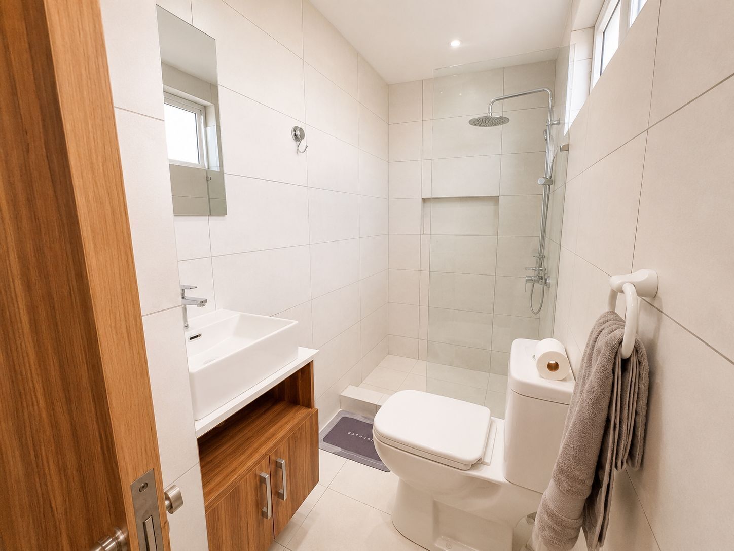 A modern bathroom with a white sink, toilet, and shower.