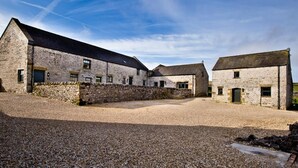 A stone building with multiple rooms, a gravel courtyard, and a clear sky. - Unique barn conversion, sleeps up to 6 in 3 bedrooms, near to High Peak Trail. (Buxton)