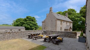 A stone building with a pitched roof and a stone wall. There are picnic tables with benches and cushions. - Unique barn conversion, sleeps up to 6 in 3 bedrooms, near to High Peak Trail. (Buxton)