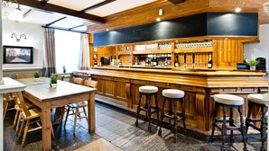 A bar area with wooden bar stools, a long counter, and a variety of bottles and glasses. - The Crewe & Harpur pub, a unique exclusive self catering venue, sleeps up to 34. (Buxton)