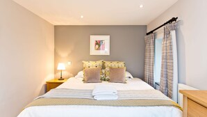 A neatly made bed with a striped bedspread, a folded towel, and patterned pillows. - Quirky barn conversion, sleeps 8 in 4 bedrooms, near to the High Peak Trail. (Buxton)