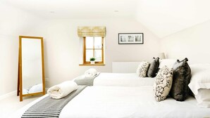 A hotel room with a large bed, a standing mirror, a window with a view, and a framed picture on the wall. - Lapwing Barns, large rural farmhouse with games room, perfect for all types of groups. (Longnor)