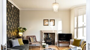 Una sala de estar con chimenea, sofá, sillón y televisión.