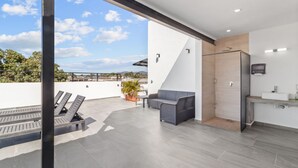 Un espace de vie extérieur moderne, comprenant un canapé, une table et une plante en pot.