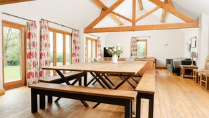 Une pièce spacieuse avec une grande table à manger en bois, des bancs et un téléviseur.