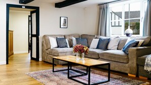 A living room with a sofa set, a coffee table, and a window with curtains.