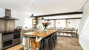 A modern kitchen with a wooden island, stainless steel appliances, and pendant lighting. - Superb barn conversion with games room, near Monyash, sleeps up to 20 in 7 bedrooms. (Monyash)