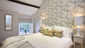 Une chambre avec un grand lit, deux lampes de chevet, une fenêtre donnant sur un beau paysage et un miroir au mur.
