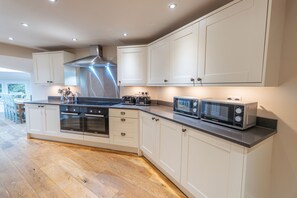 A modern kitchen with built-in appliances, wooden flooring, and white cabinetry.