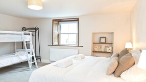 A bedroom with bunk beds, a window, a radiator, a shelf with decorative items, and a bedside lamp. - The Star in Taddington, 9 bedroom exclusive venue. Close to Buxton and Bakewell. (Buxton)