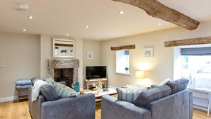 A cozy living room with a stone fireplace, a flat-screen TV, and comfortable seating. - The Star in Taddington, 9 bedroom exclusive venue. Close to Buxton and Bakewell. (Buxton)