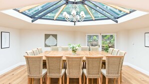A dining area with a large wooden table, wicker chairs, a chandelier, and a skylight above. - The Star in Taddington, 9 bedroom exclusive venue. Close to Buxton and Bakewell. (Buxton)
