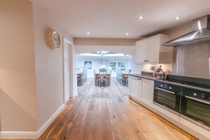 A modern kitchen with a Bosch oven, wooden flooring, and a view to a dining area. - The Star in Taddington, 9 bedroom exclusive venue. Close to Buxton and Bakewell. (Buxton)