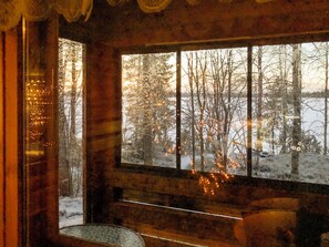 Quarto com uma janela grande que dá para uma paisagem nevada, um banco e uma mesa.