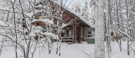 Uma cabana de madeira rodeada por árvores cobertas de neve.