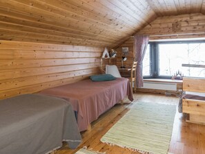 Habitació d'una cabana acollidora, amb llit, cadira, escriptori i finestra.