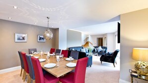 A dining area with a wooden table set for six, surrounded by red and grey upholstered chairs. - Modern 5 bedroom family friendly barn conversion in the heart of Bakewell. (Bakewell)