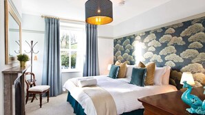 A bedroom with a bed, a chair, a desk, a mirror, and a window with curtains. - Victorian country house with 9 ensuite bedrooms, nestled in a pretty hamlet (Buxton)