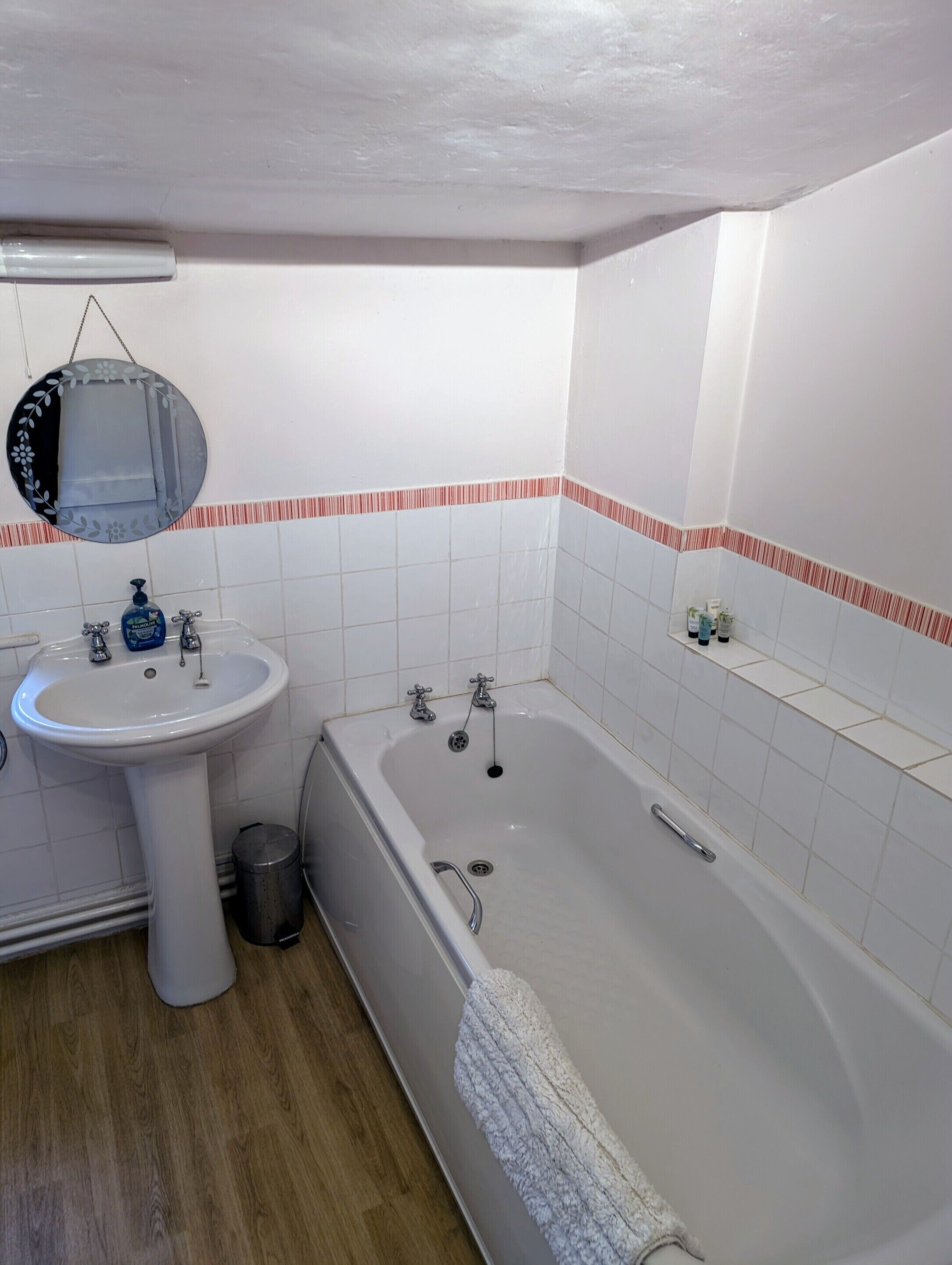 A bathroom with a sink, mirror, and bathtub.