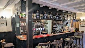 A bar with Guinness taps, wooden stools, and a counter with a menu. - Bartholomew Arms (Towcester)