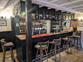A bar with Guinness taps, wooden stools, and a counter with a menu.
