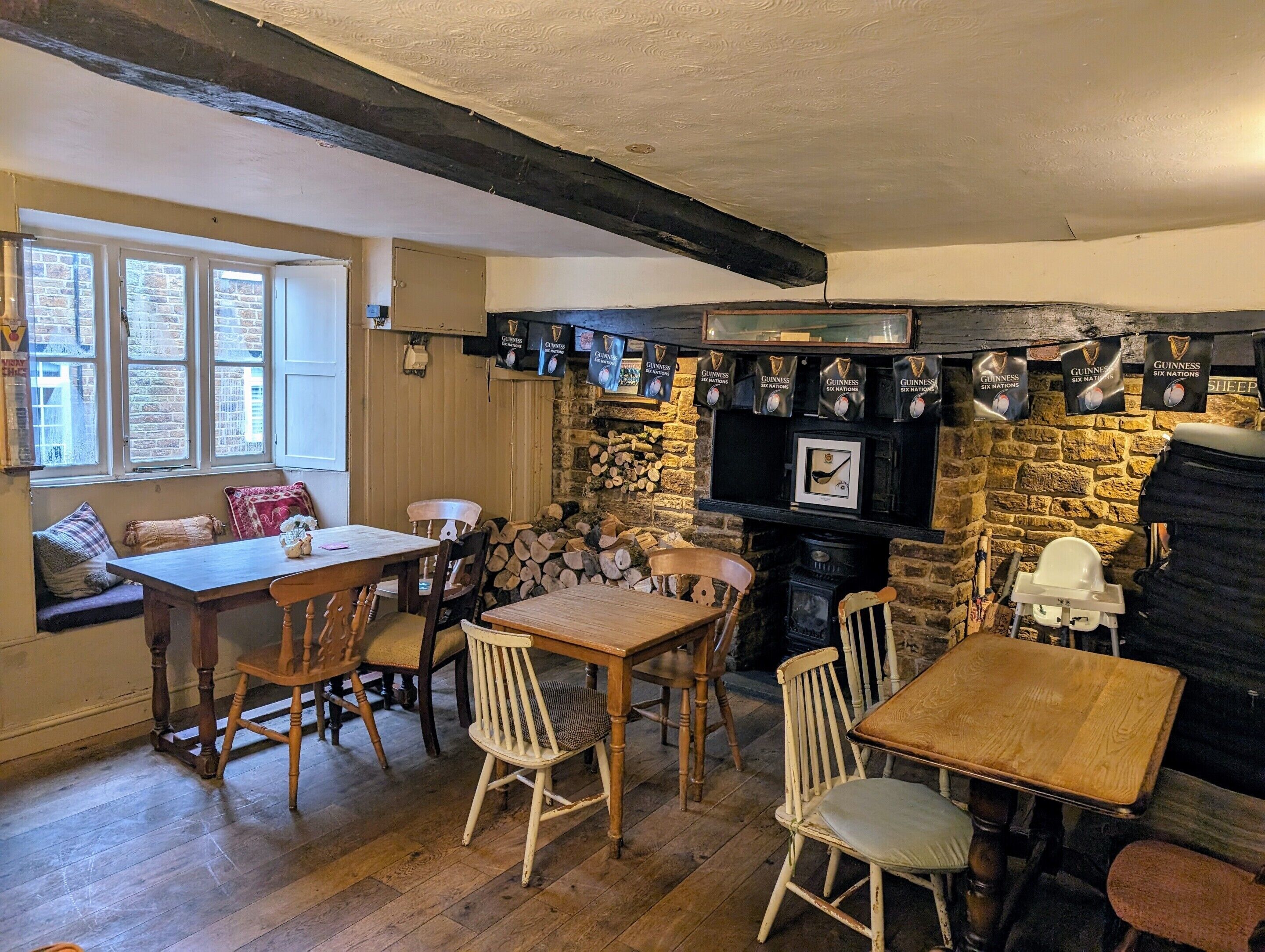 A cozy pub with wooden furniture, a stone wall, and Guinness banners.