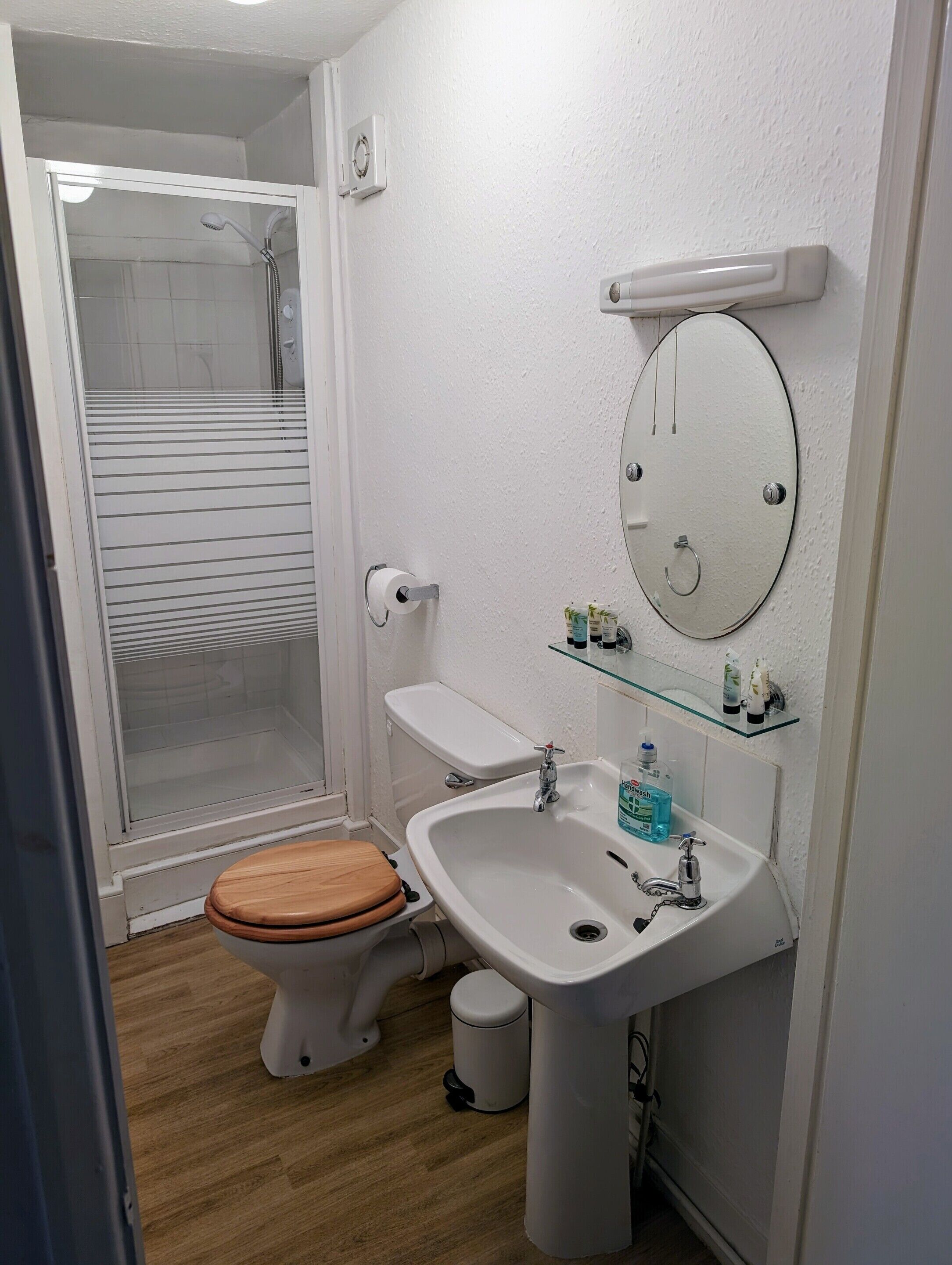 Een kleine badkamer met toilet, wastafel en douche.