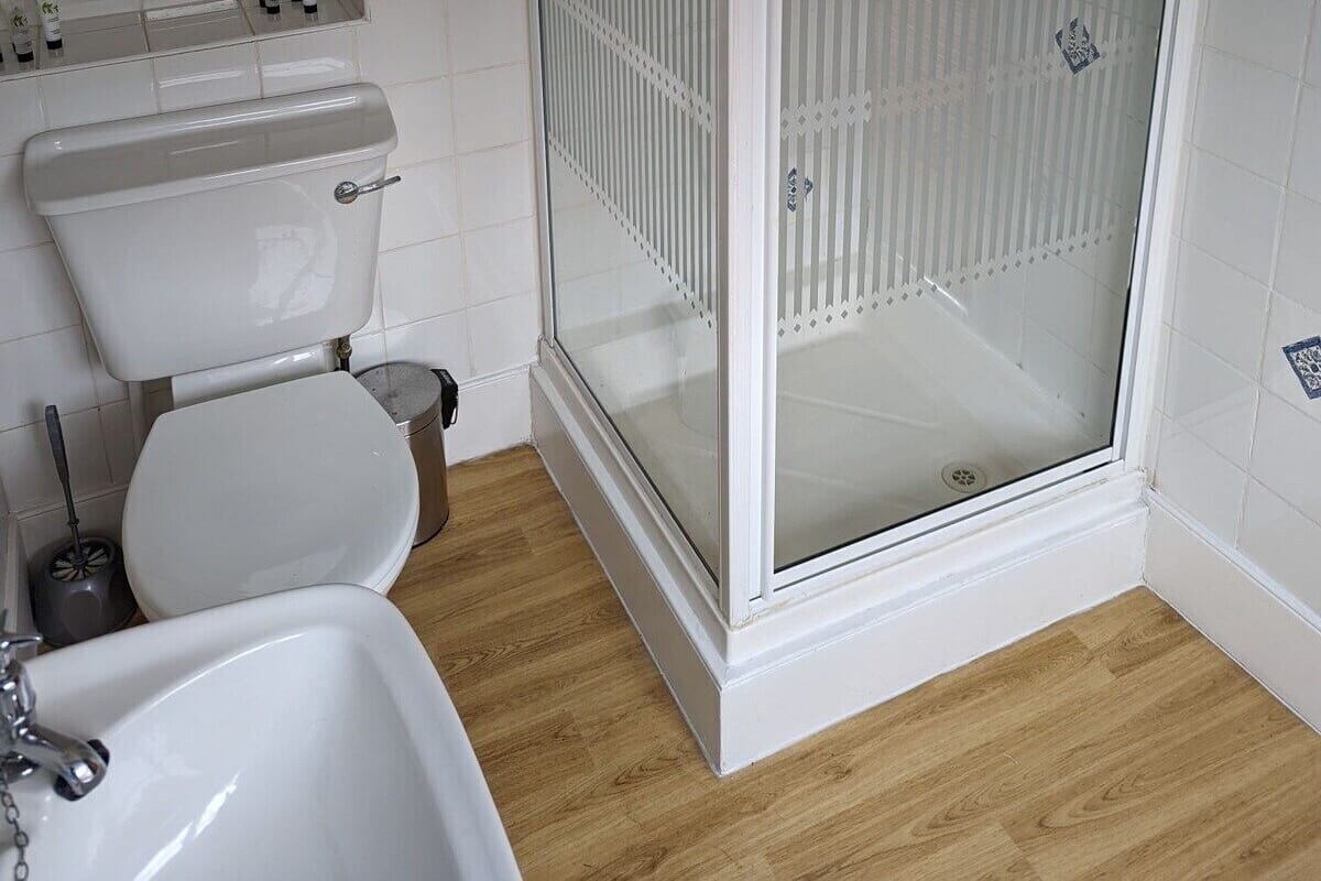 A bathroom with a white toilet, a sink, and a glass-enclosed shower.