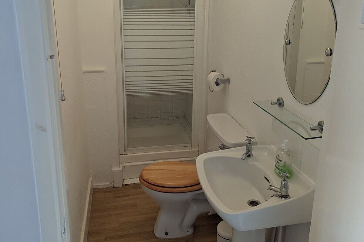 A small bathroom with a toilet, sink, and shower.