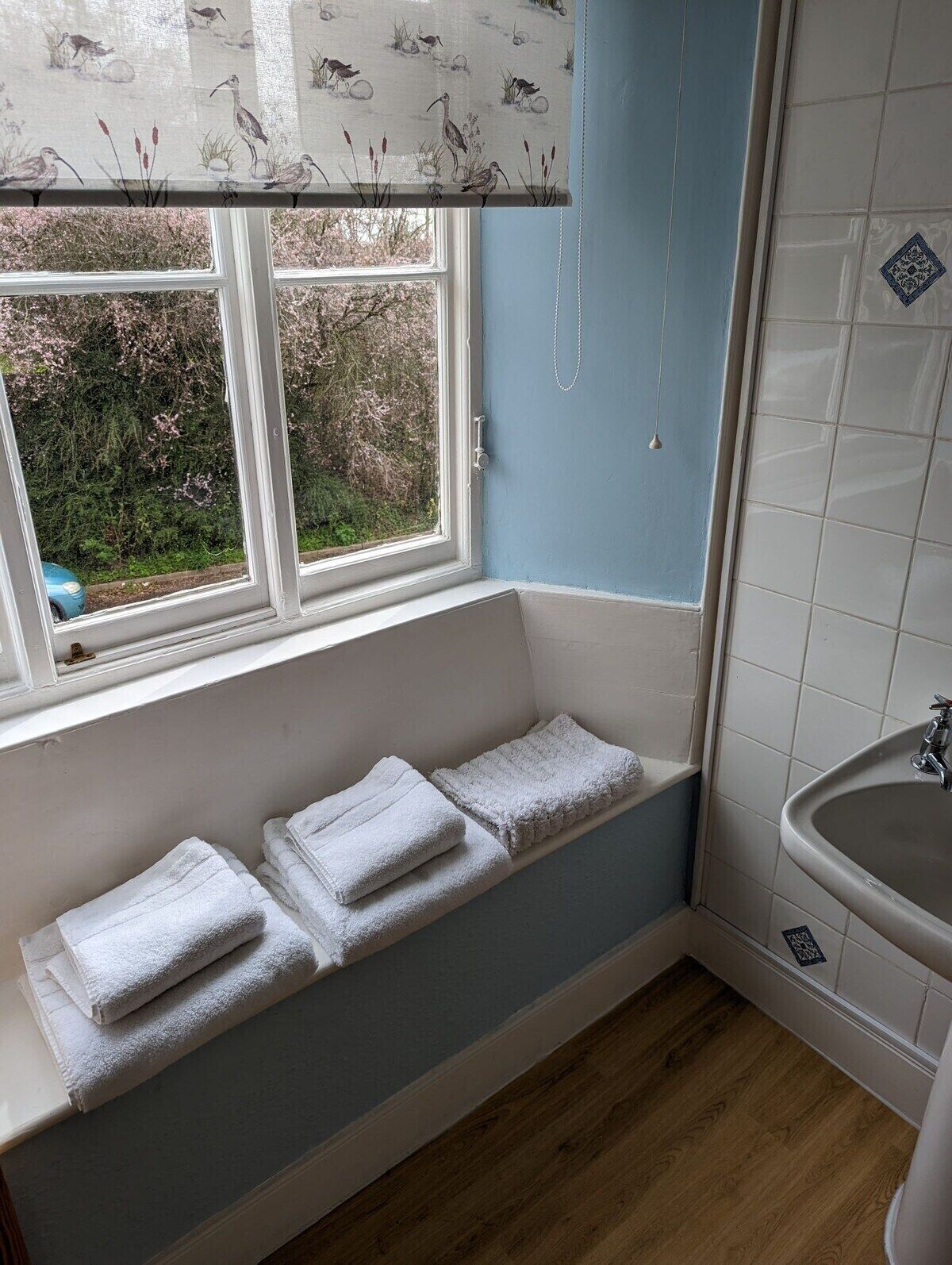 Ein Badezimmer mit Fenster, Badewanne und Waschbecken.