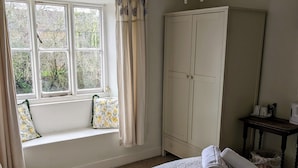 A bedroom with a large window, a wardrobe, a bed with checkered bedding, and a chandelier. - Bartholomew Arms (Towcester)