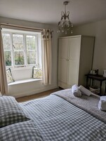 A bedroom with a large window, a wardrobe, a bed with checkered bedding, and a chandelier.