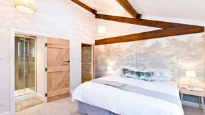 A bedroom with a large bed, a wooden door, a stone wall, and a forest-themed mural. - Large luxury farmhouse retreat situated in a rural hamlet, perfect for large gatherings of up to 50 (Matlock)