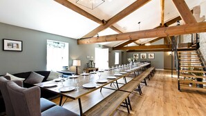 A long dining table set for a meal with wooden beams and a staircase in the background. - Large luxury farmhouse retreat situated in a rural hamlet, perfect for large gatherings of up to 50 (Matlock)