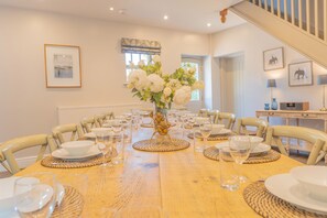 A dining room with a long table set for a meal, surrounded by chairs. - Traditional stone barn in the pretty village of Wetton, close the Manifold Valley. (Ashbourne)