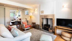 A living room with a sofa, armchairs, a fireplace, a television, and a dining area in the background. - A cosy country cottage in the village of Curbar with amazing views of Curbar Edge (Curbar)