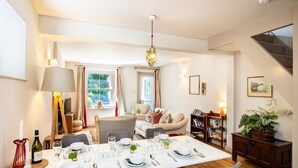A dining area with a table set for four, a sofa, a bookshelf, and a staircase. - A cosy country cottage in the village of Curbar with amazing views of Curbar Edge (Curbar)