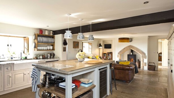 Une cuisine spacieuse dotée d’un îlot central, de meubles en bois et d’une cheminée en pierre.