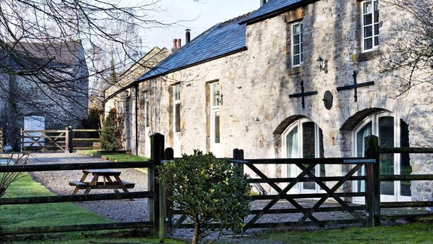 A stone building with multiple windows and a cross on the facade. - Collection of 4 charming barns offering group accommodation for 16, close to Bakewell (Bakewell)