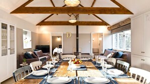 A dining area with a wooden table set for a meal, surrounded by chairs. - Collection of 4 charming barns offering group accommodation for 16, close to Bakewell (Bakewell)