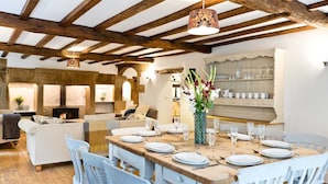 A dining area with a wooden table set for a meal, surrounded by white chairs. - Traditional 5 bedroom stone built farmhouse, near Monsal Trail and Bakewell. (Bakewell)
