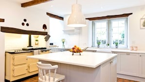 A kitchen with a large island, white cabinetry, a hanging pendant light, and a window with a view of greenery. - Traditional 5 bedroom stone built farmhouse, near Monsal Trail and Bakewell. (Bakewell)