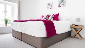 A bedroom with a bed, a nightstand, a window with curtains, and a plant. - Cosy 2 bed cottage nestled in the village of Bradwell, close to the Hope Valley (Bradwell)