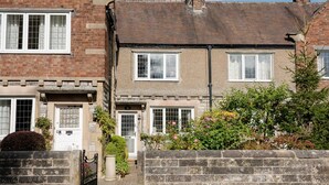A row of terraced houses with distinct brick facades and white window frames. - Quaint 2 bedroom cottage in the picturesque village of Ashford-in-the-Water. (Bakewell)