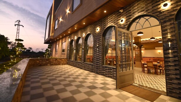 A modern building with a checkered floor, arched windows, and a stone facade. - Hotel ShyamLeela - Khatushyamji (Shri Madhopur)