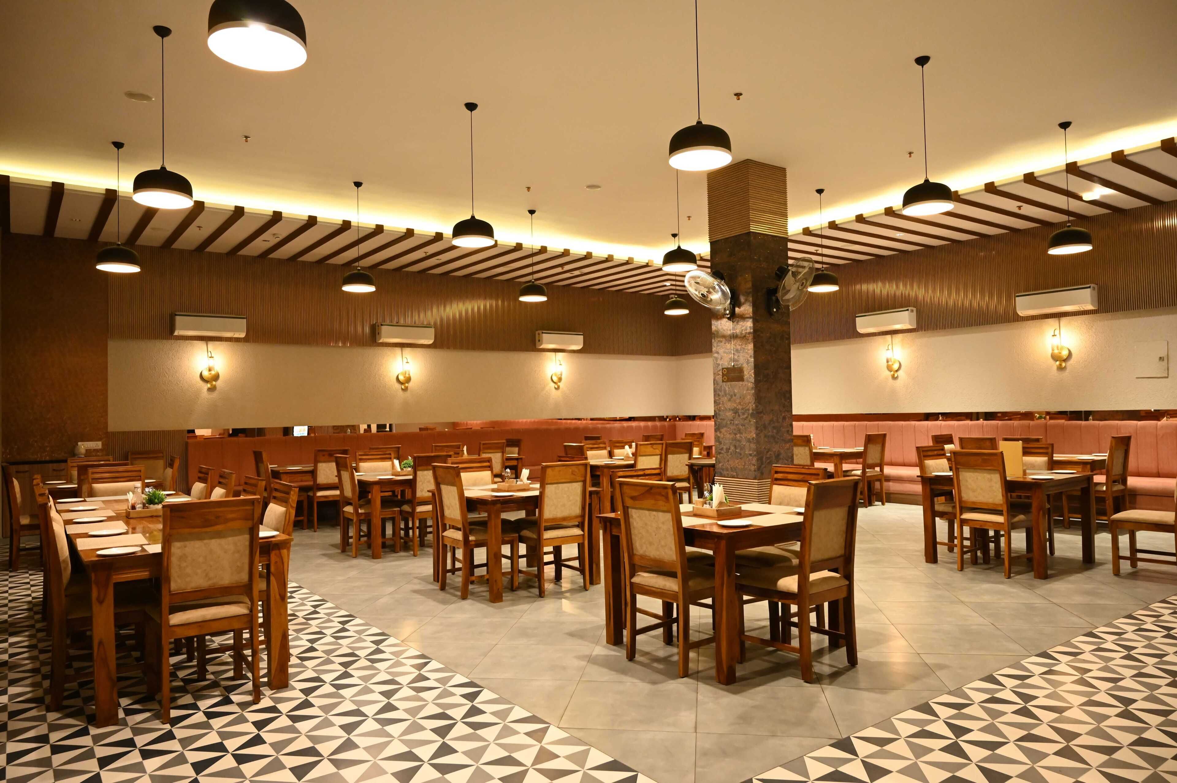 Un restaurante con varias mesas y sillas, paneles de madera en las paredes e iluminación colgante.